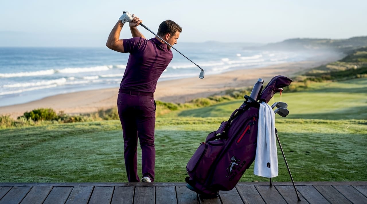 Golfer mid-swing on green practice area