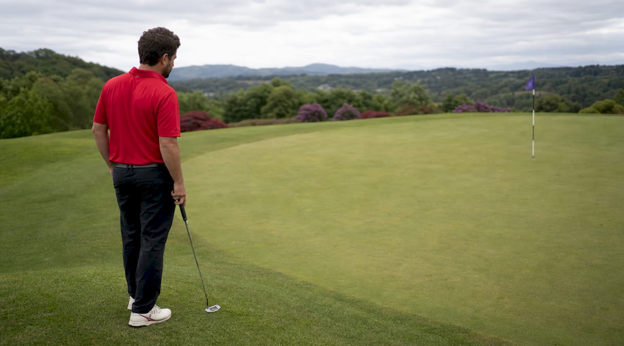 Un golfista analiza el terreno antes de hacer su tiro en el campo de golf.