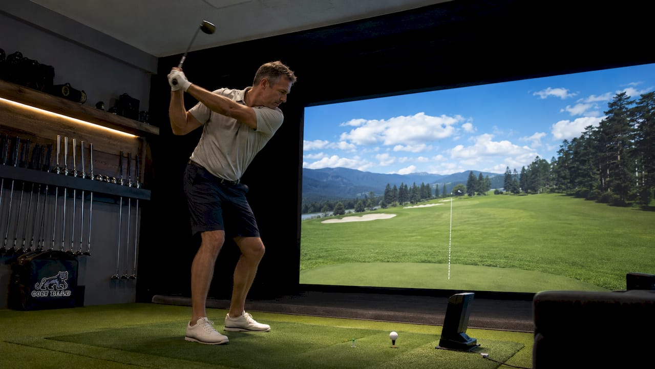 Man practicing golf swing inside golf simulator room