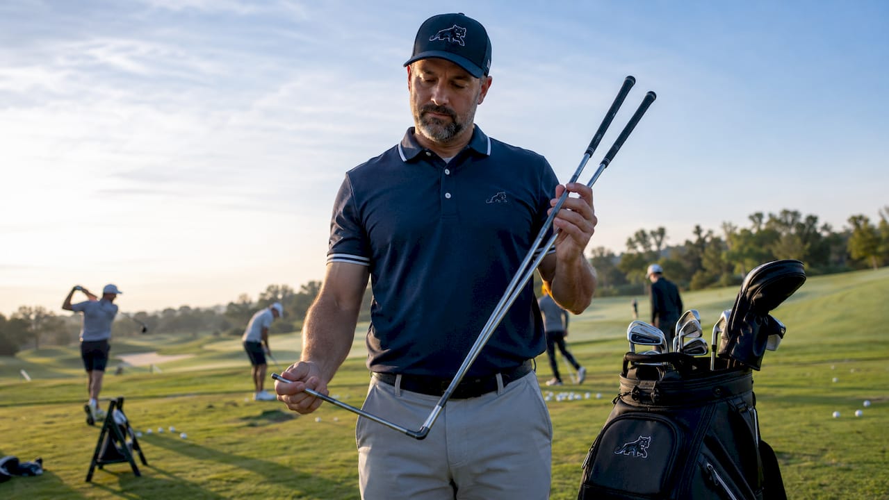 Golfer comparing flex of two golf shafts outdoors