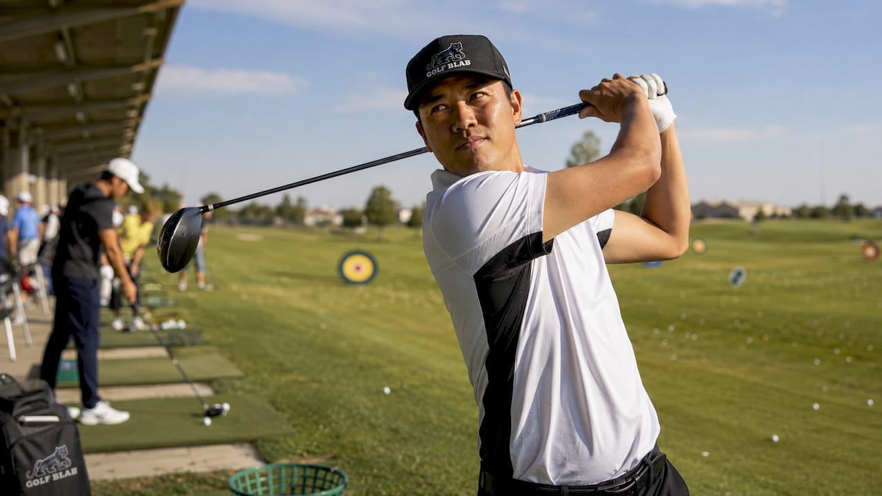 Golfer practicing swing at dawn on driving range
