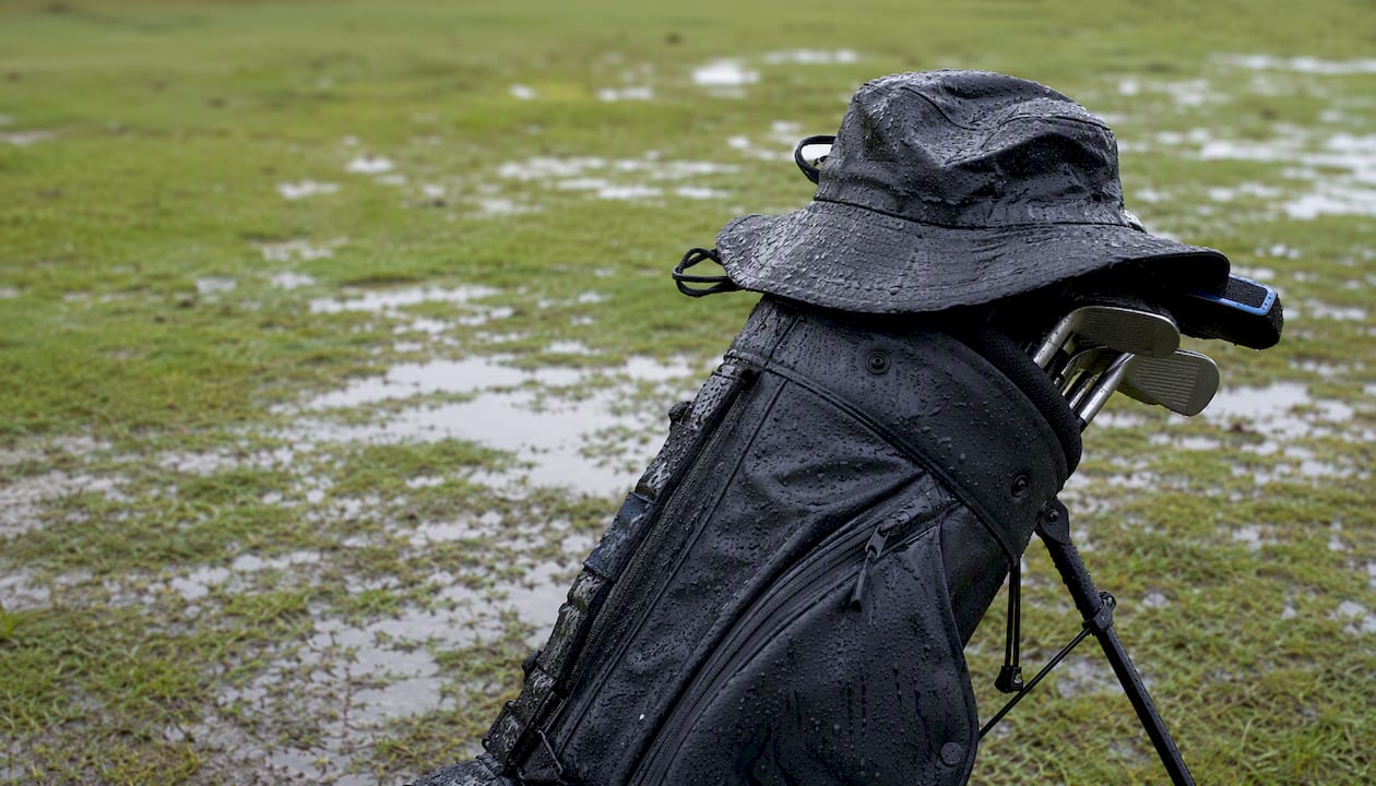 Wet golf gear arranged on damp grass