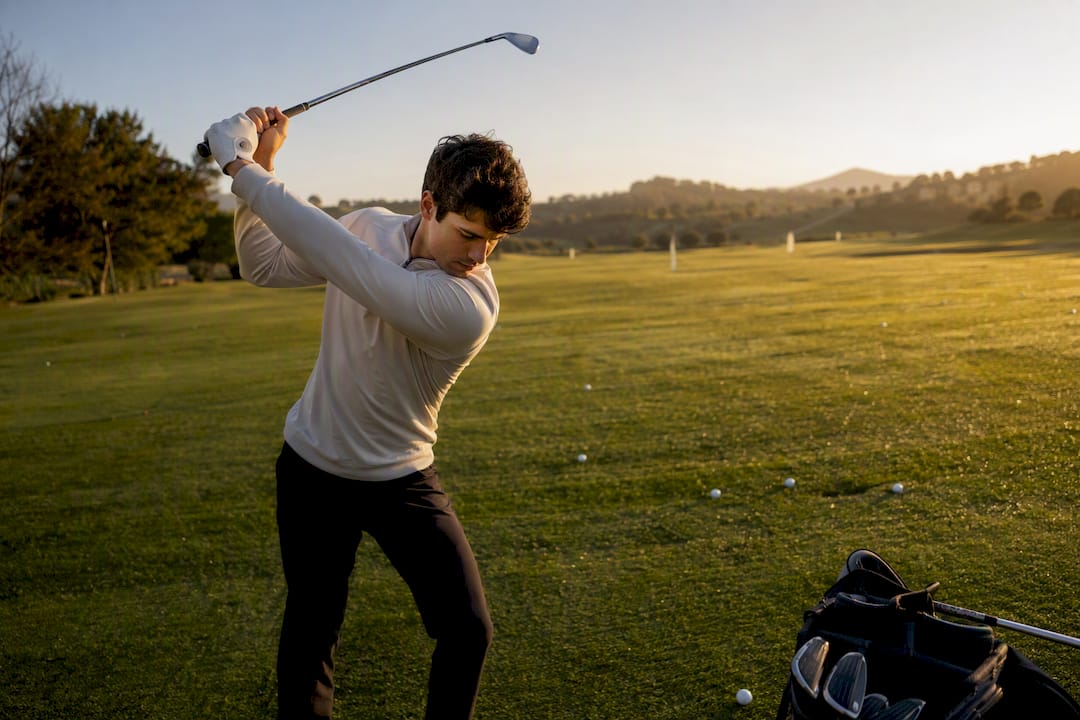 Golfer mid-swing at practice range