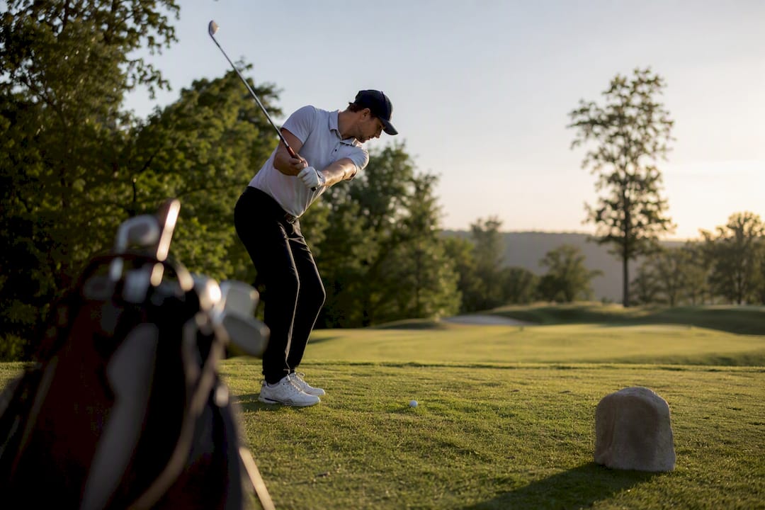 Golfer adjusting swing posture on tee box
