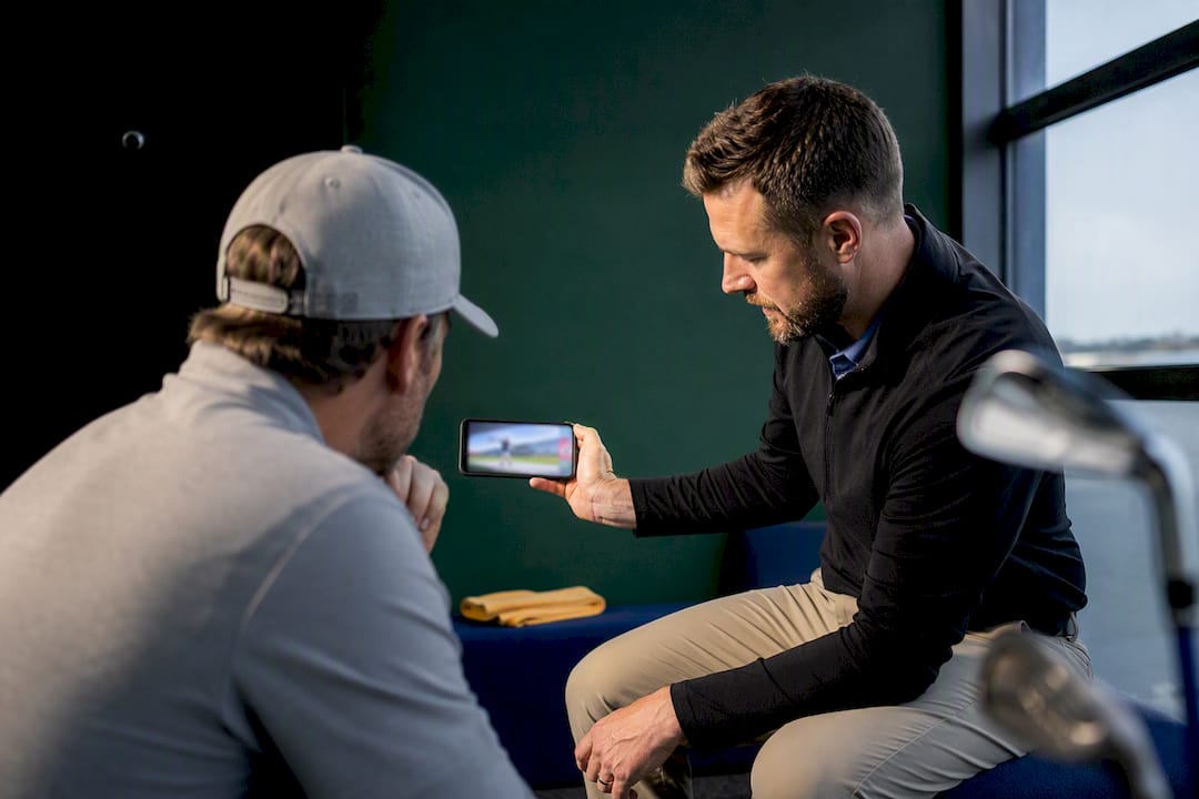 Golfer reviewing swing video with coach