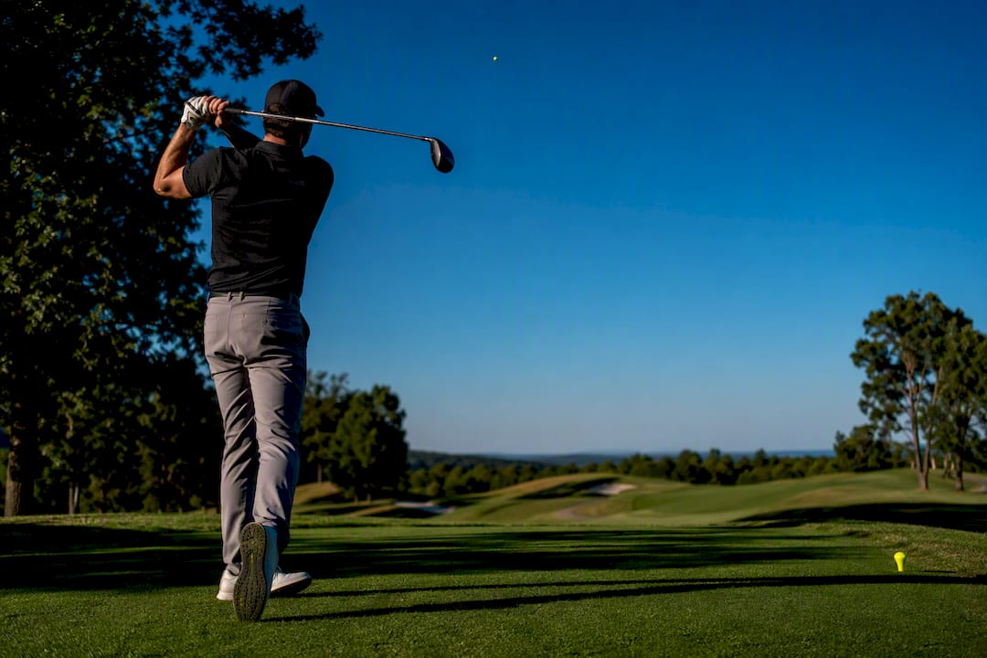 Golfer tracking chartreuse ball against sky
