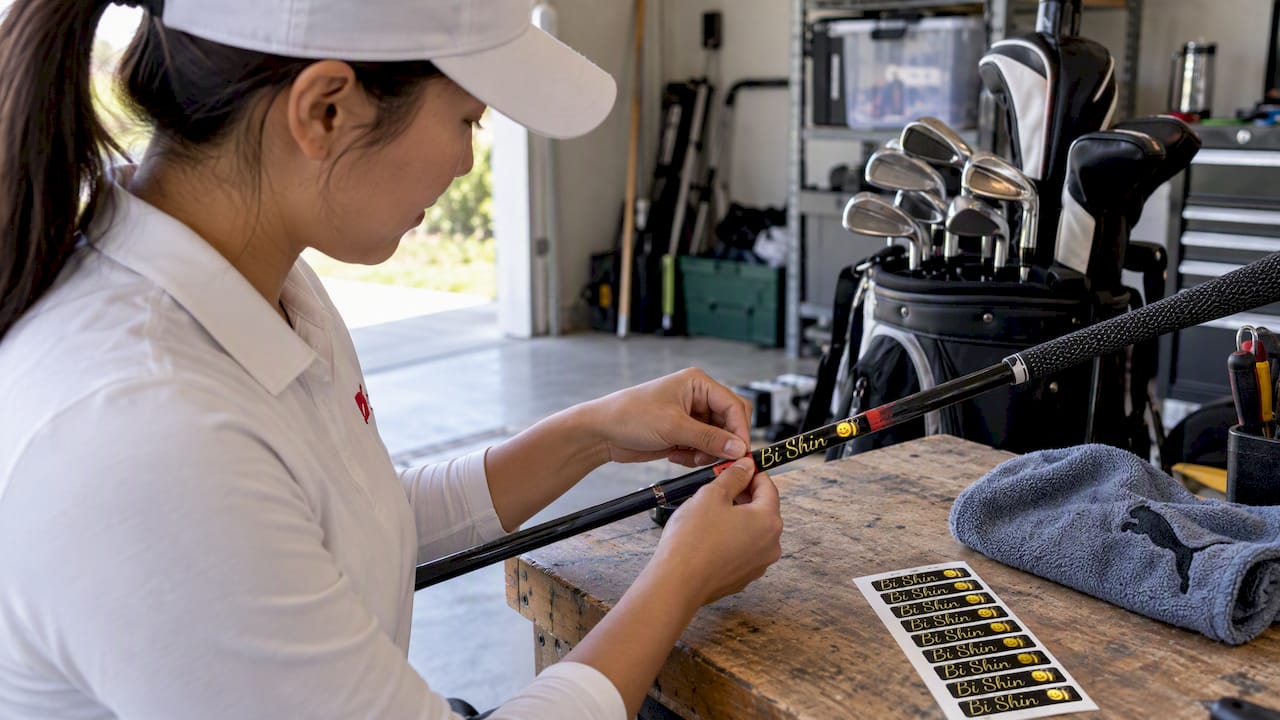 Golfer applying custom label to golf club