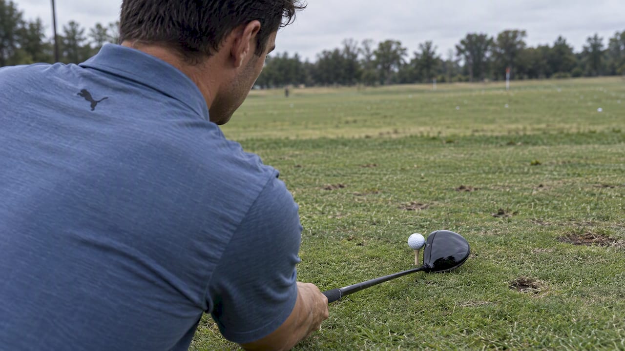 Golfer aligning ball with driver crown